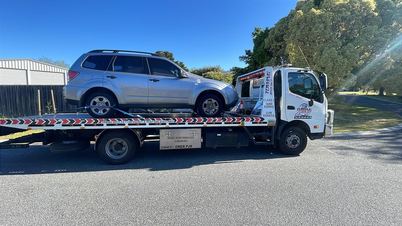 Towing Boys 24/7 flatbed truck loading a silver Subaru Forester on a suburban Perth street