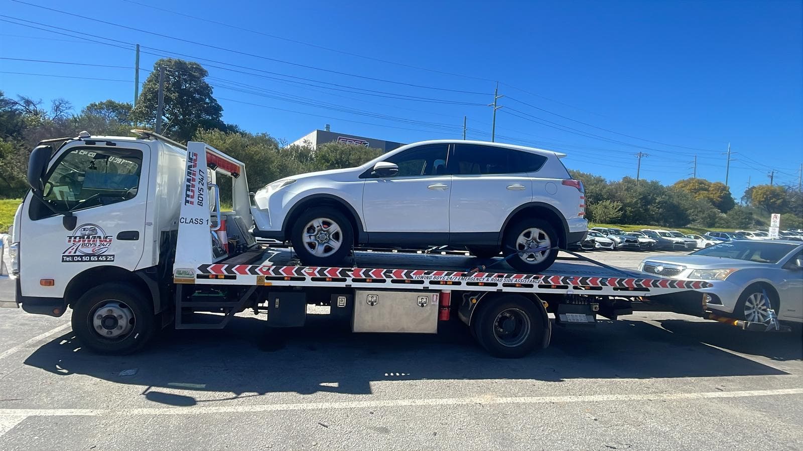 Tow truck transporting a white Toyota RAV4 from a Perth car dealer yard