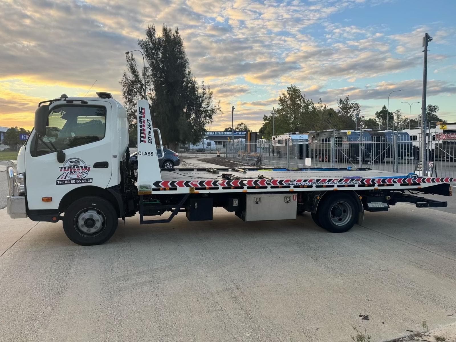 Towing Boys 24/7 flatbed tow truck parked at sunset, ready for dispatch