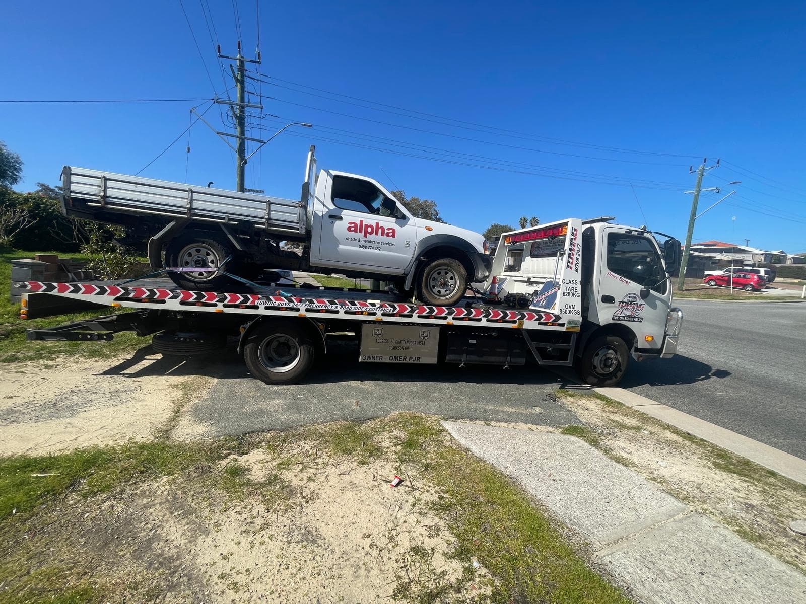 Towing Boys 24/7 truck transporting a tradesman's work ute with shade and membrane signage